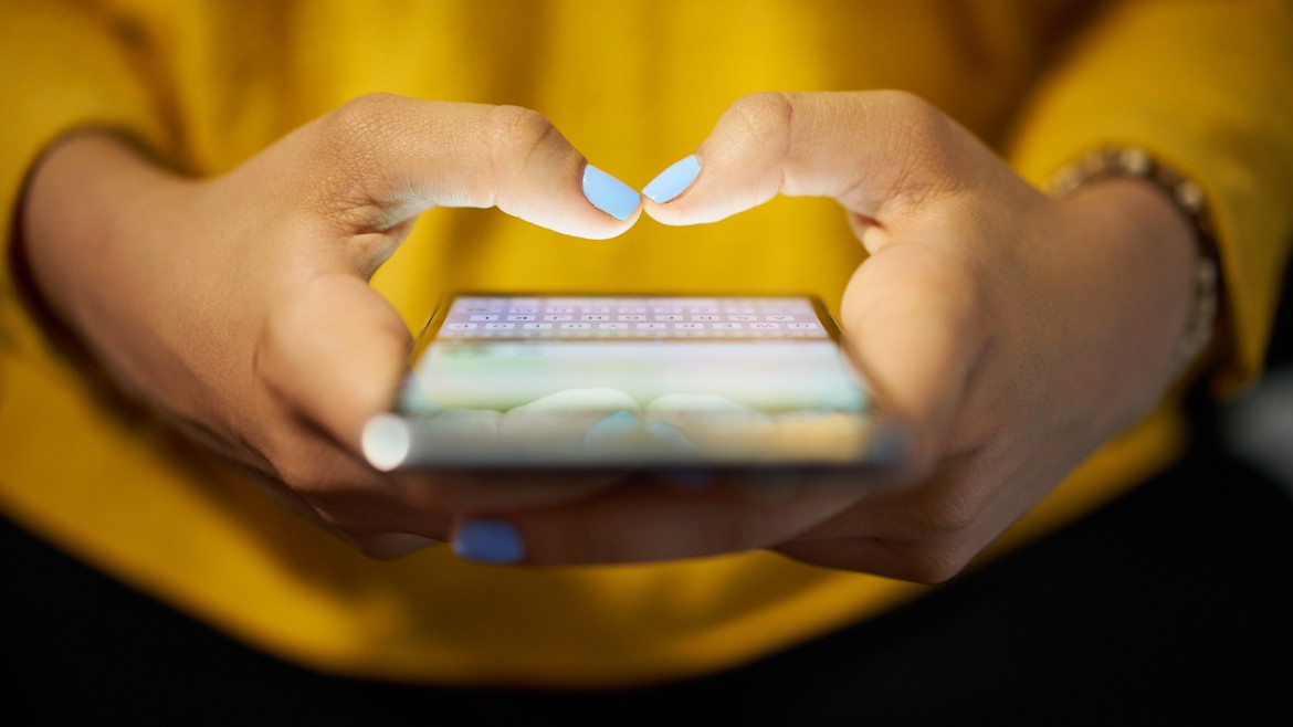Eine Frau mit bunt lackierten Nägeln tippt auf einem Smartphone rum