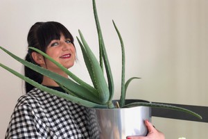 Ágota Dimén mit langen schwarzen Haaren und einer Pflanze vor dem Gesicht