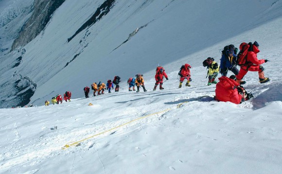 Sherpas sind mit einer Gruppe Touristen und einem Kameramann am Mount Everest unterwegs