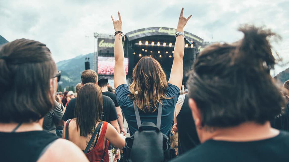 Eine Frau steht in einer Menschenmenge vor der Bühne des Greenfield Festivals und hält die Arme hoch