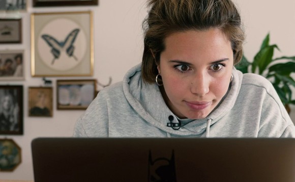 Host Jara Helmi sitzt mit starrem Blick hinter ihrem Laptop