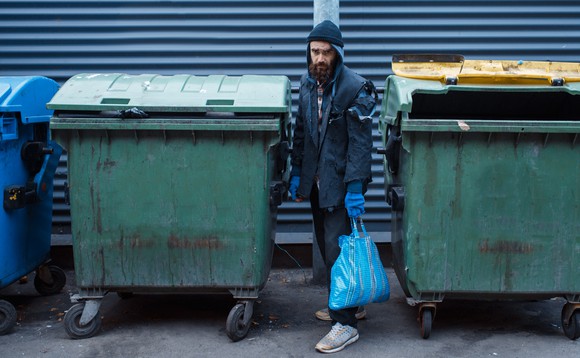 Ein Mann steht zwischen zwei Abfalltonnen auf der Strasse in Paris