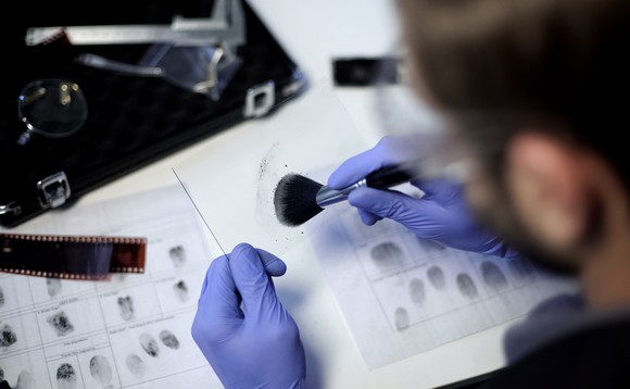Ein Forensiker untersucht Fingerabdrücke, welche er an einem Tatort gesichert hat