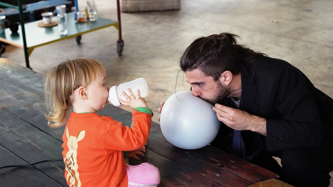 Vater und Kind spielen in der Grossraumhalle mit einem Ballon