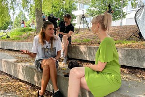 Lea Spirig spricht mit Model Tamy Glauser auf einer Treppenstufe, ein Kameramann filmt das Gespräch.