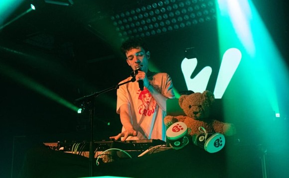 Musiker Nemo steht mit einem Mikrofon in der Hand an den Turntables