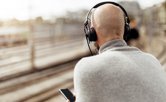 Ein Mann hat sich Kopfhörer aufgesetzt und hört einen Podcast