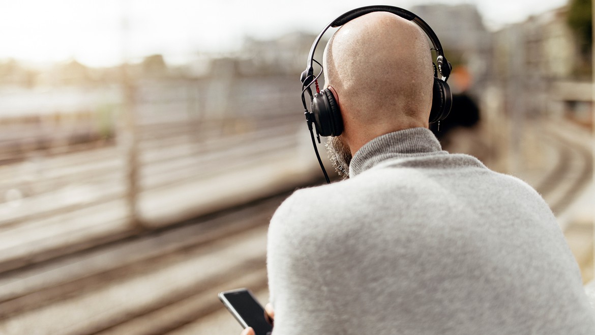 Ein Mann hat sich Kopfhörer aufgesetzt und hört einen Podcast