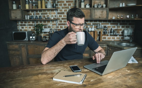 Ein Mann sitzt an einem Tisch und arbeitet an seinem Computer.