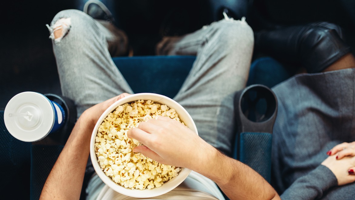 Jemand sitzt im Kino und isst Popcorn