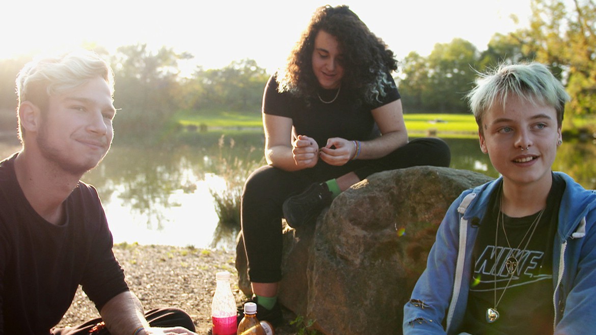 Protagonist Emil sitzt mit zwei Freunden an einem Weiher