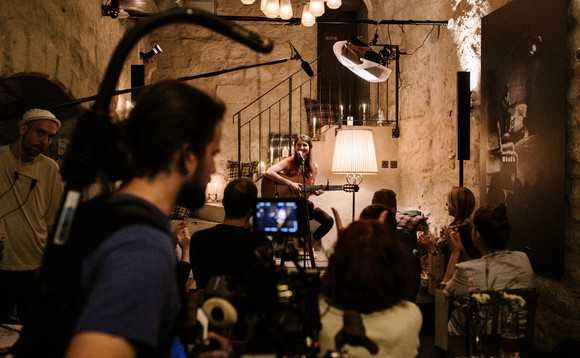 Hauptdarstellerin Lorena Handschin sitzt mit ihrer Gitarre vor dem Mikrofon in einem Club