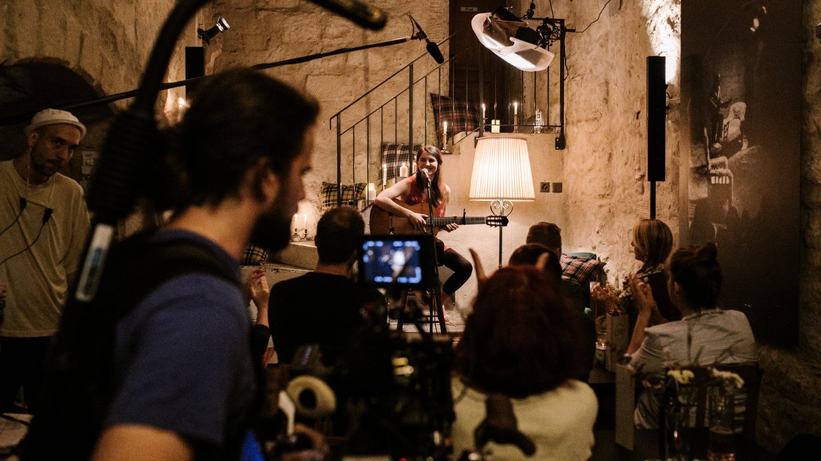 Hauptdarstellerin Lorena Handschin sitzt mit ihrer Gitarre vor dem Mikrofon in einem Club