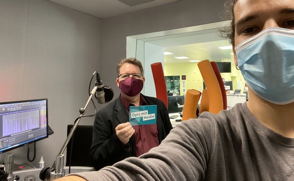 Praktikant Jan steht mit Philip Meyer im Radiostudio. Beide tragen Mundschutz und halten Abstand.
