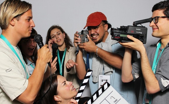 Sechs junge Leute bei einem Photobooth mit Kameras, Mikrofonen und Filmklappe in der Hand