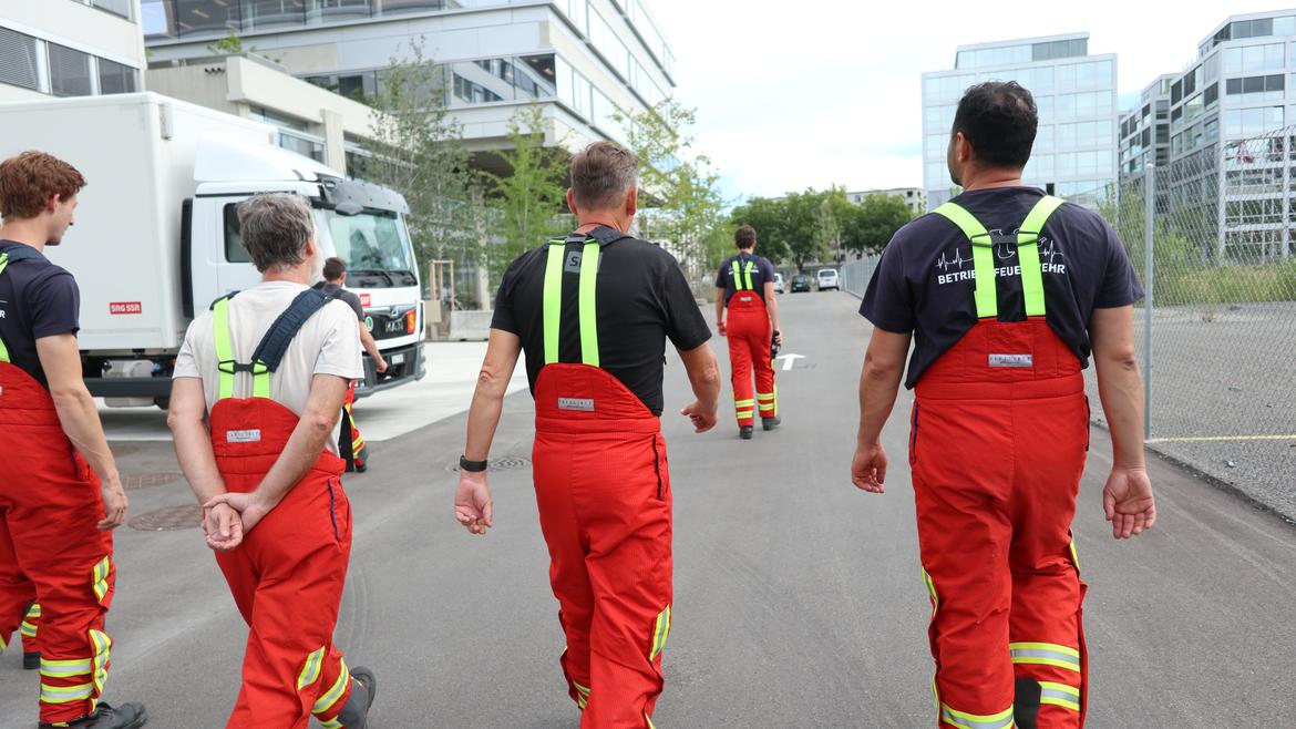 Vier Feuerwehrleute laufen in Montur die Strasse runter