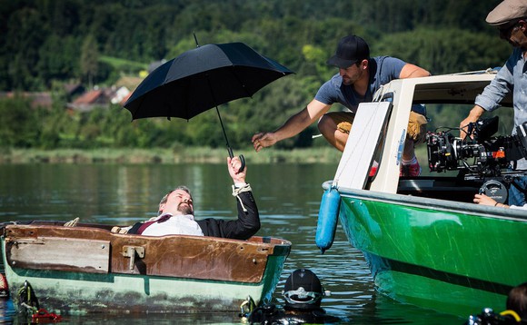 Set von «Der Bestatter». Mike Müller liegt in einem Boot im Wasser, hält dabei einen Schirm.